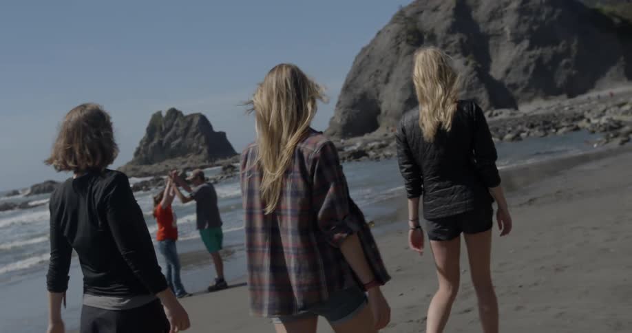 A group of women walk down the beach