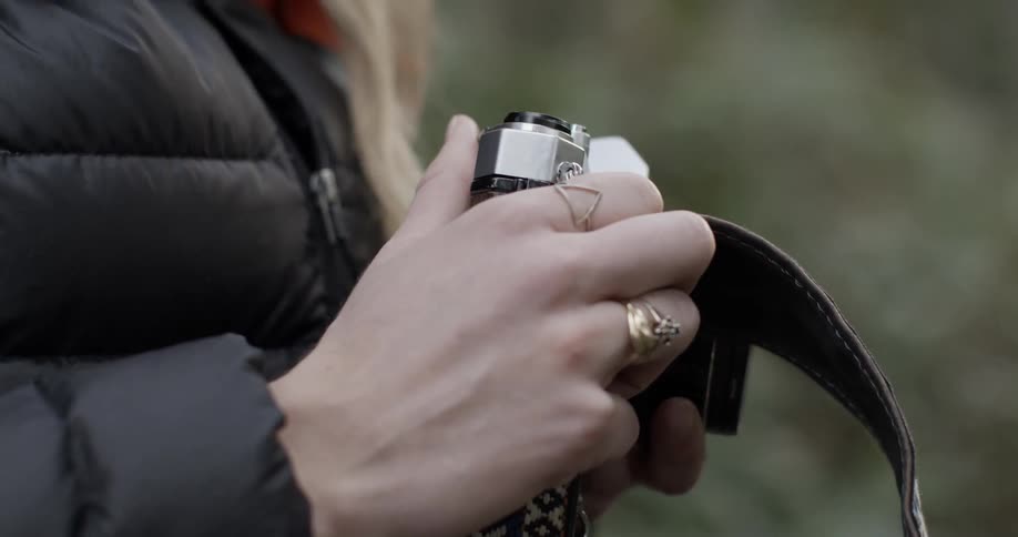 A woman holds a camera near her chest