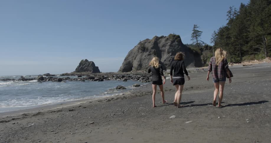 Three women are walking together on the beach