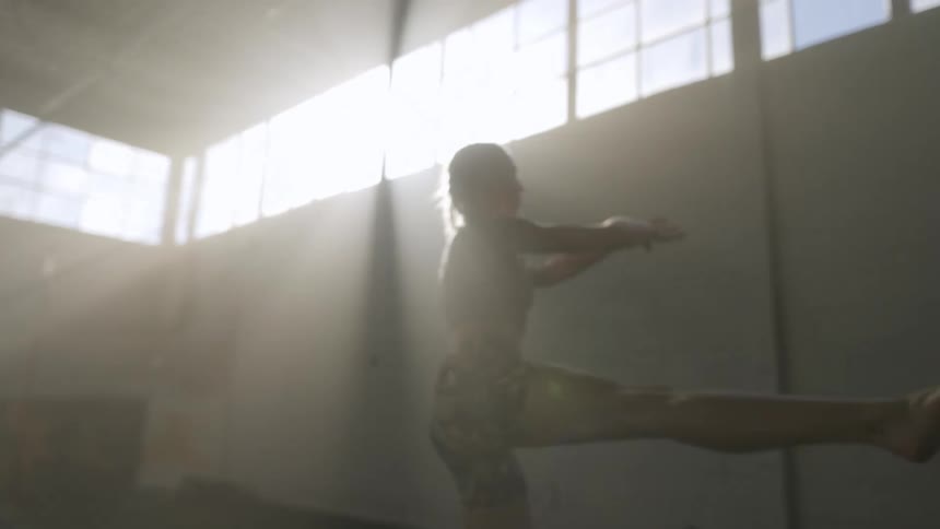 A woman in a room jumping and skipping with a wall in the background