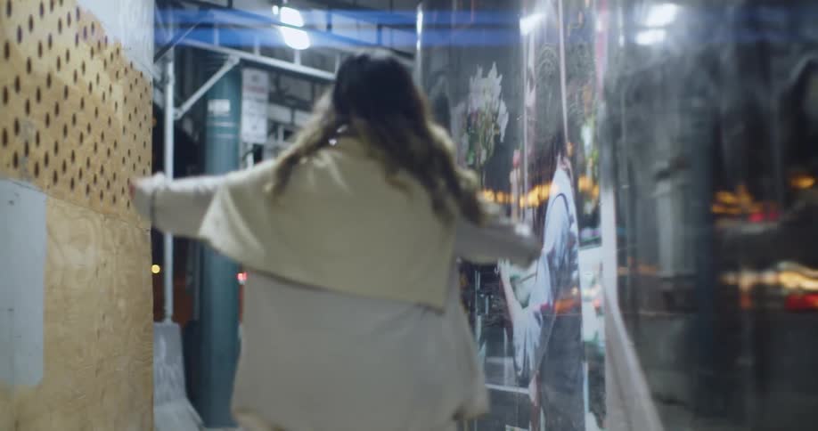Young woman dancing on a hallway near a city street at night