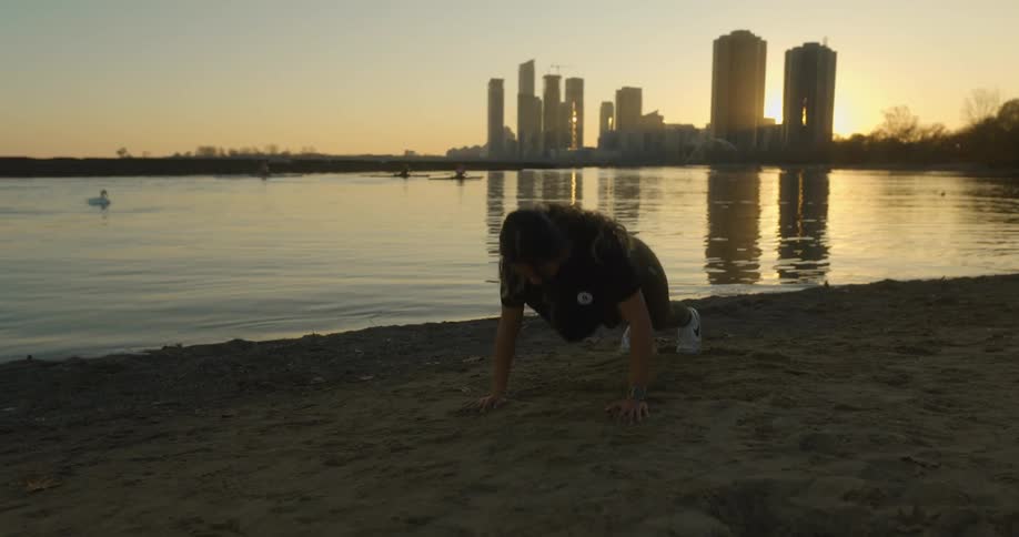 A woman exercising next to a lake with skyscrapers in the distance