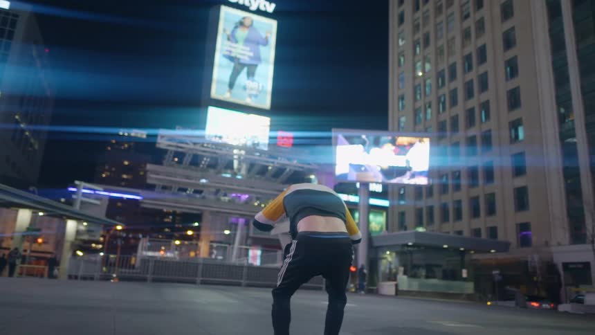 A man standing in a downtown plaza performs an impressive standing back flip and lands successfully