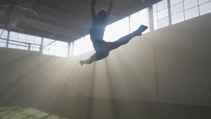 Young fit woman in sports clothes running and jumping inside a gym at morning