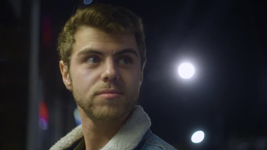A man standing in front of bright lights outside at night