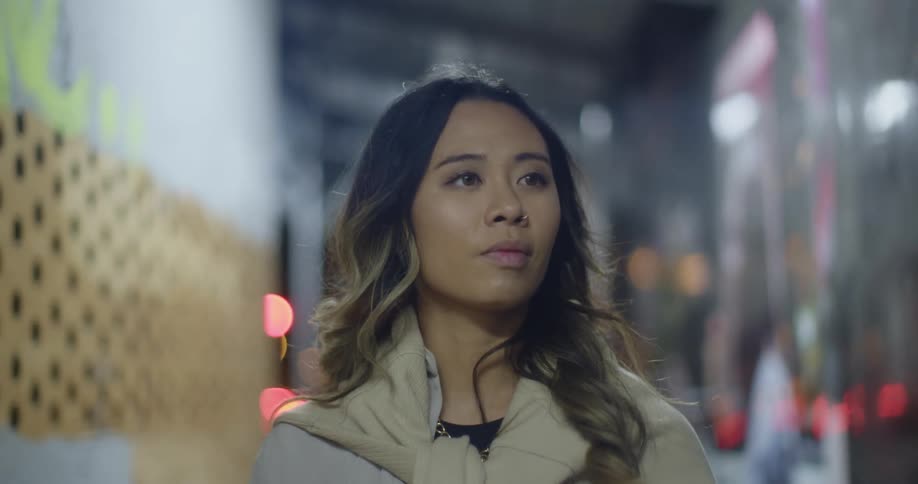 A woman walks through a subway station where murals are painted on the walls