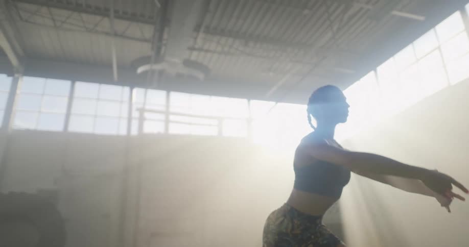 A dancer balancing on one leg in a sunny fitness room