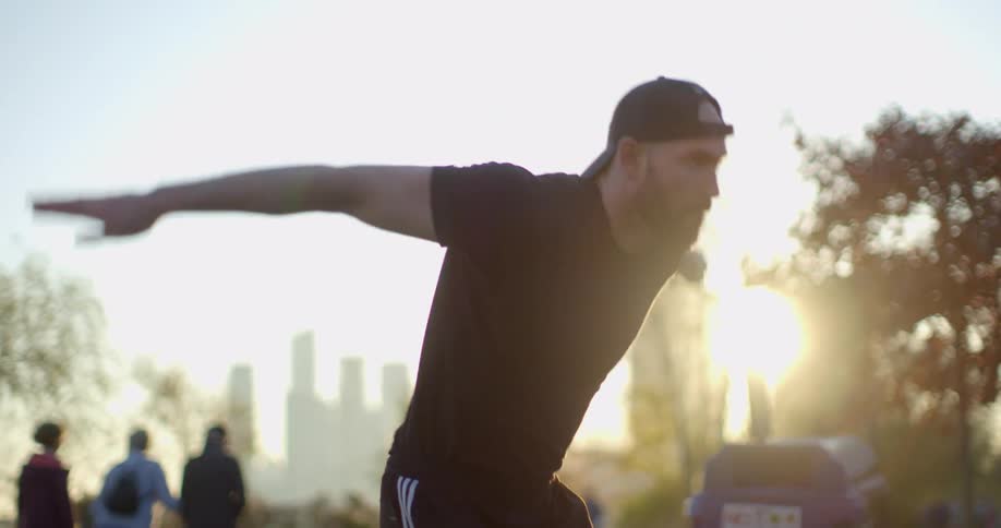 A man prepares for and does a backflip in a city park near downtown