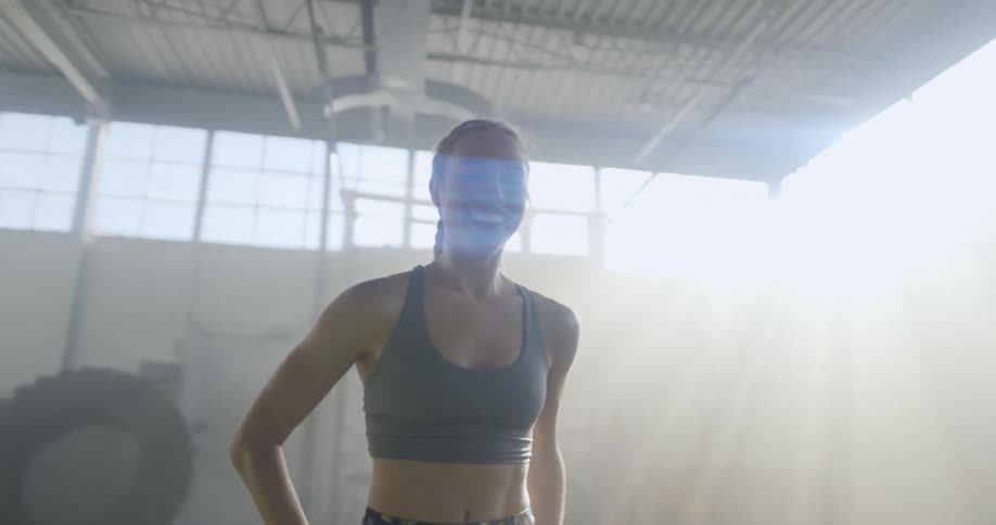 A woman in a room standing and laughing with a wall and tires in the background