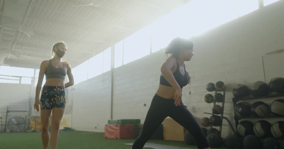 Two fit women wearing sports clothing practice yoga in a gym on a sunny day