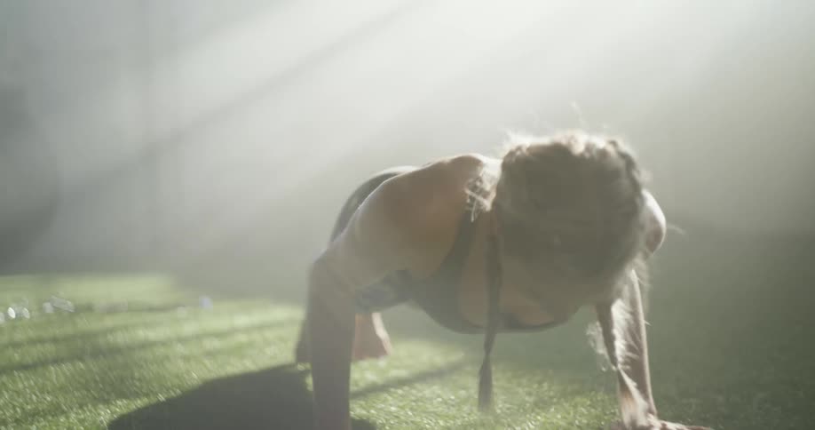 Young fit blonde woman stretches under the morning sunlight on the floor of a gym