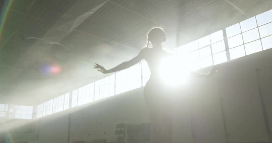 A woman jumps and raises her arms up while doing ballet plies