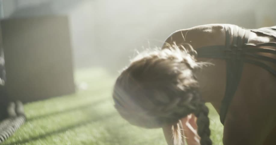 A woman stretches her arm upwards above herself while exercising indoors