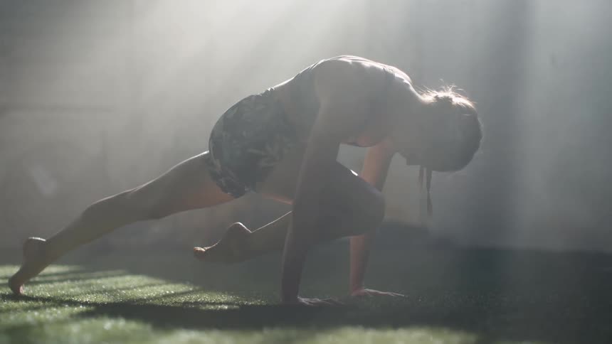 A woman stretches her leg while working out in a fieldhouse