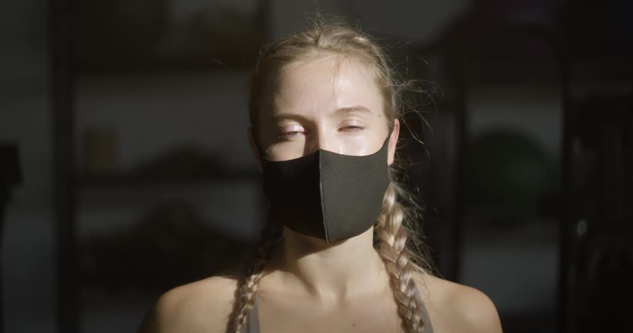 A woman with pigtail braids poses while wearing a black face mask