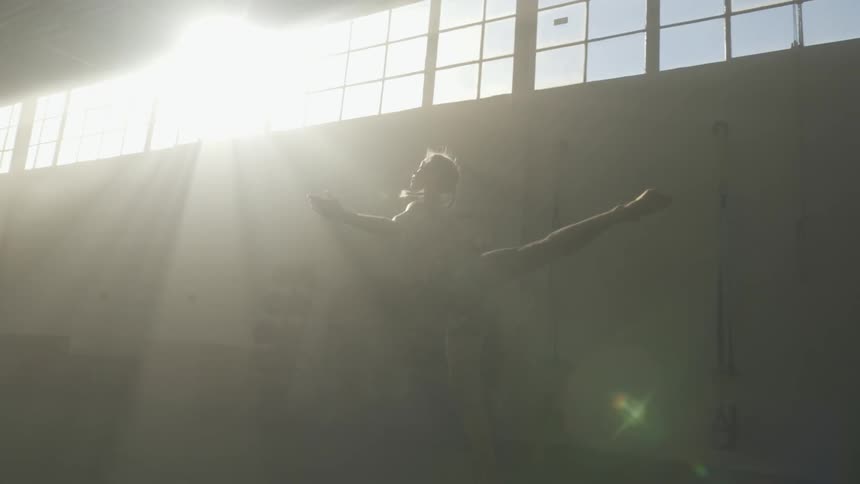 A female dancer jumping in a sunny studio