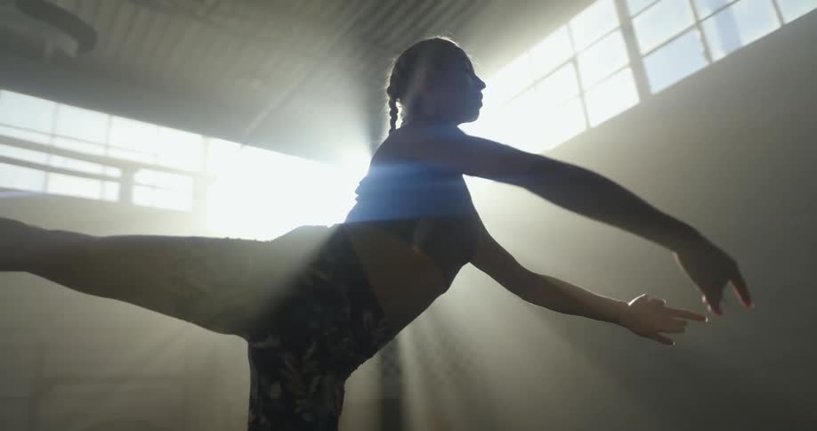 A woman is dancing and stretching indoors