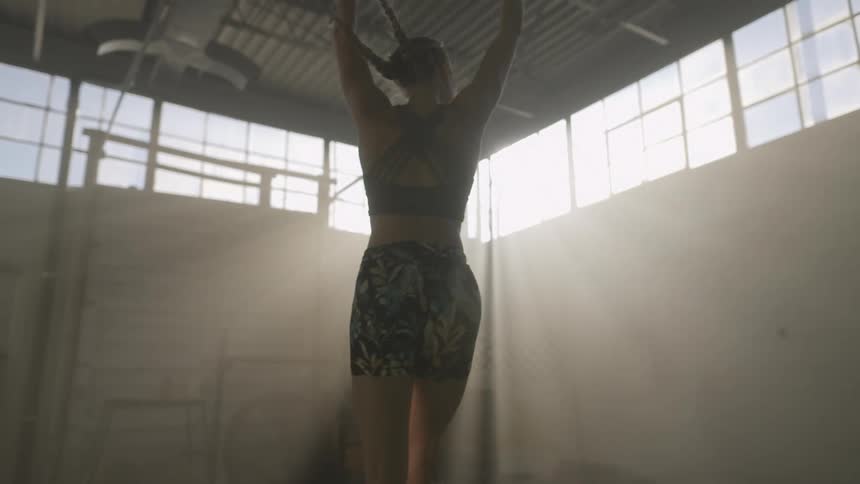 A female jumps and dances around in a large open room with sunlight in the windows