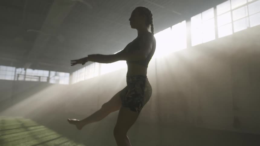 Young fit woman performing dance moves in a gym at morning