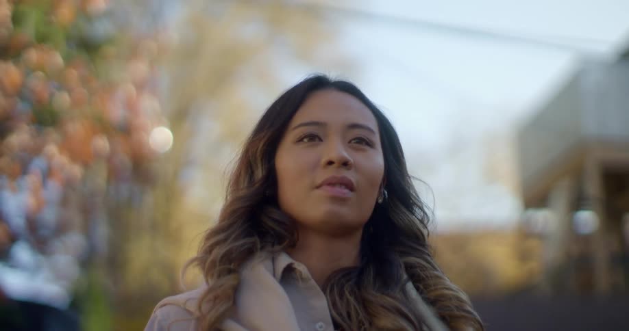 A young woman looks around as she walks outside