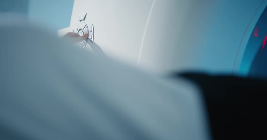A person pushing a button on a mri scanner as another person moves into it