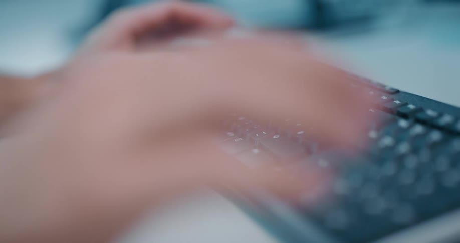 A person sitting at a desk using a mouse and typing on a keyboard