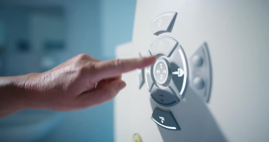 A woman presses and holds buttons on a dial turning a machine on