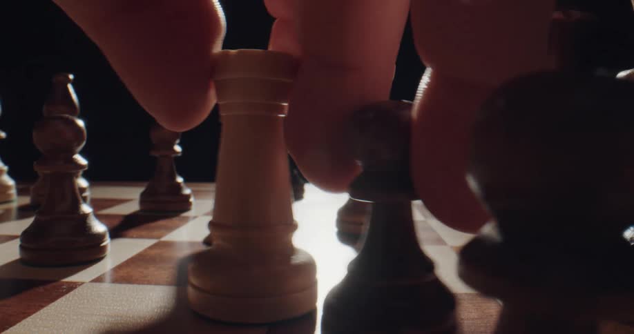 A chess player moves a piece toward another piece and moves those two pieces together to a third piece