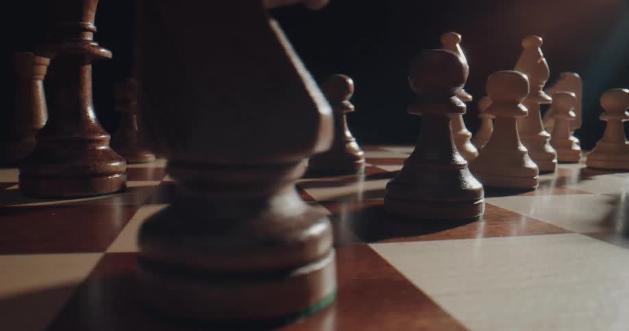 A chess player moves a piece across the board