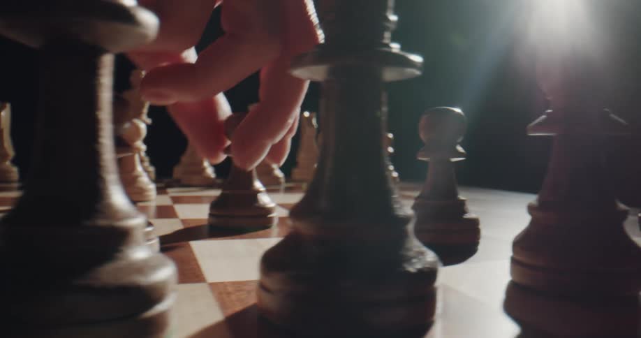 A chess player moves a piece on the board