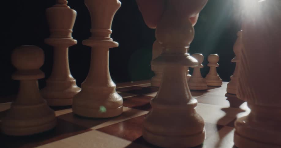 A person moves a chess piece across a board