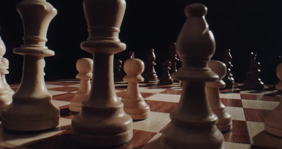 Close up of a brown and cream chess board and chess pieces