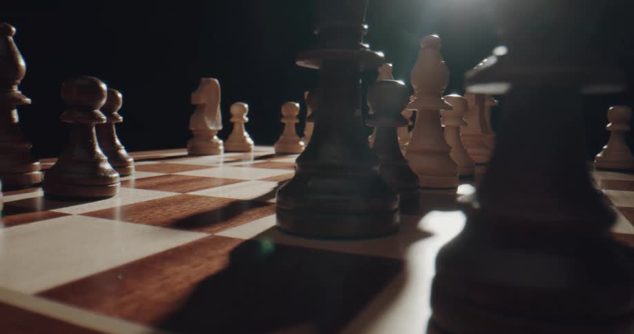 Light glares down onto a wooden chess board set with chess pieces