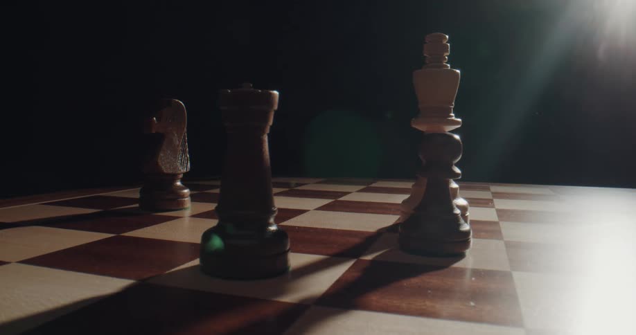 A person is placing chess pieces over a chessboard in a dark room