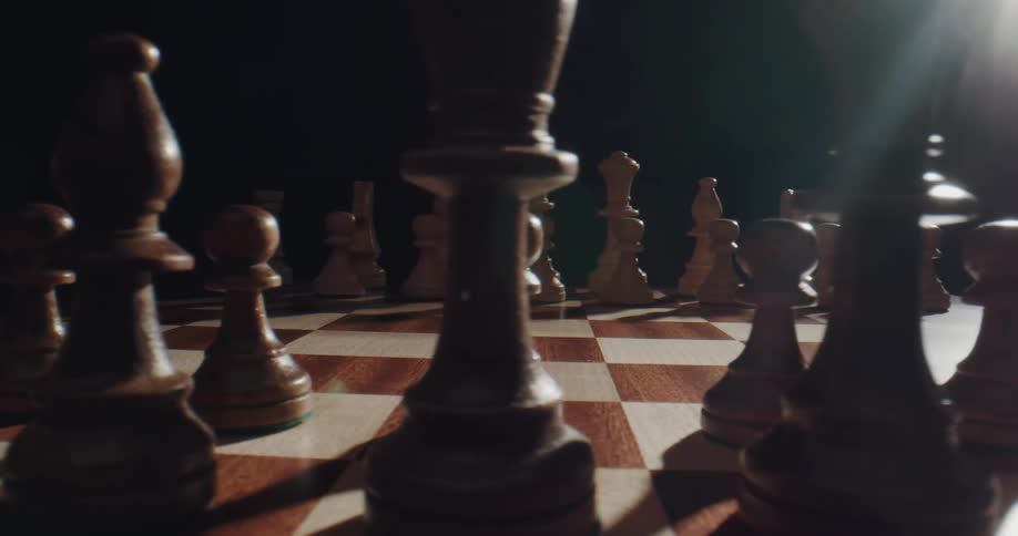 Chess pieces over a chessboard under a bright spotlight