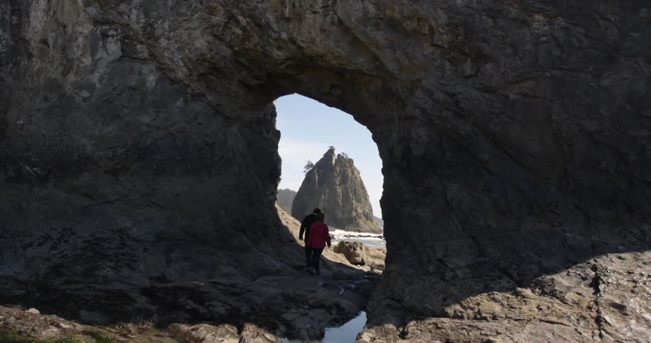 People walking through an opening in a rock formation