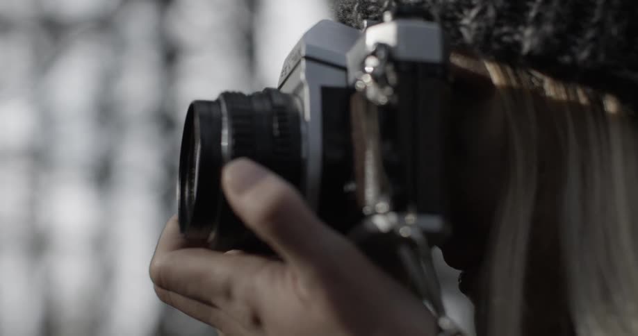 A woman takes a photograph outside on a cold day