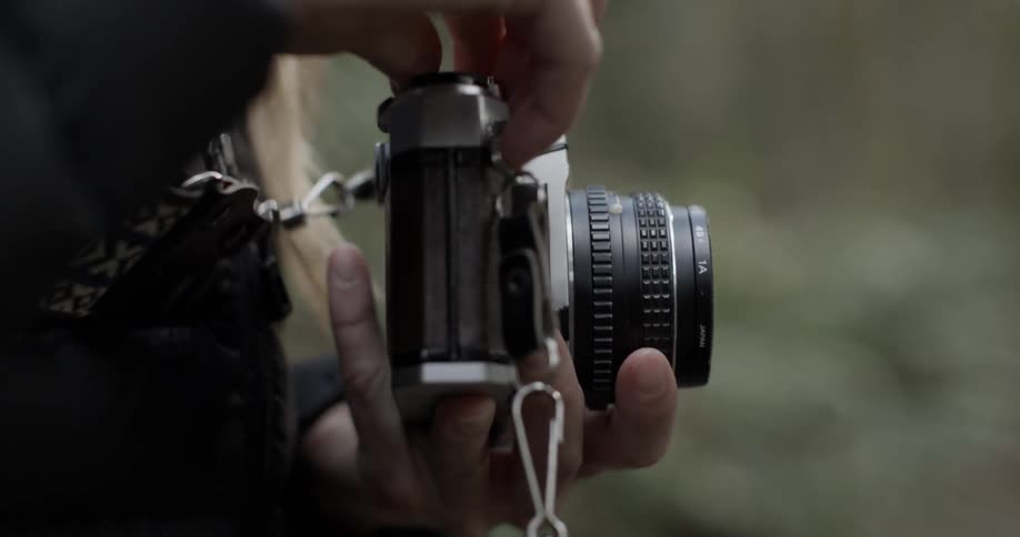 A woman holds a camera outside
