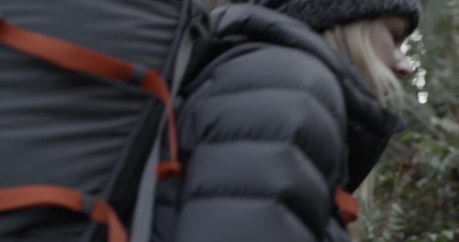 A woman hikes in the woods with a large backpack