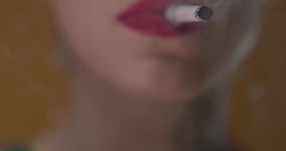 A woman is having a cigarette lit with a lighter and smoking