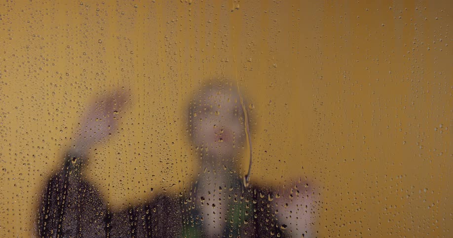 A person in a dance pose with a glass with water drops in the foreground