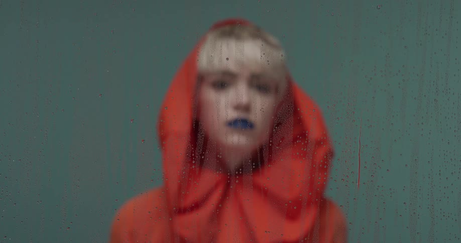 A woman is standing outdoors and wearing a rain coat