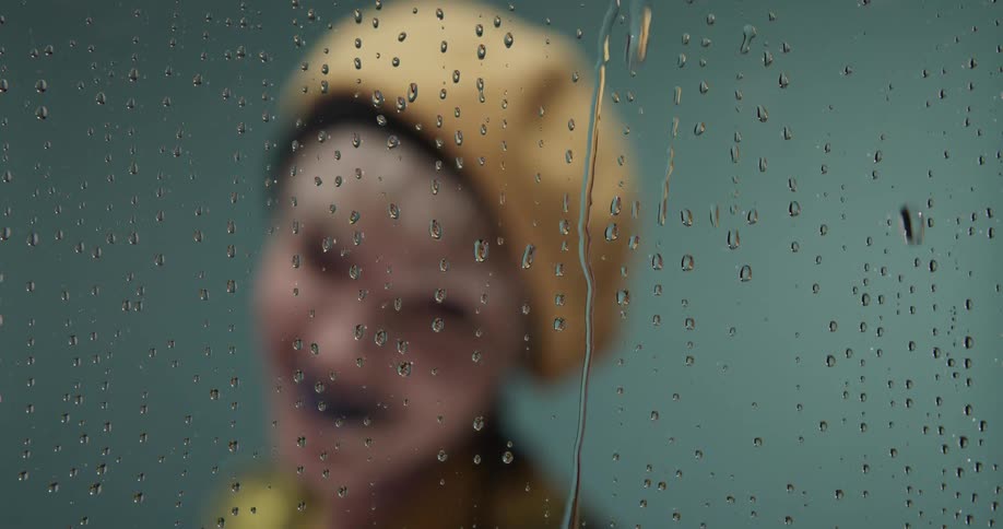 A woman is wearing a hat next to a window