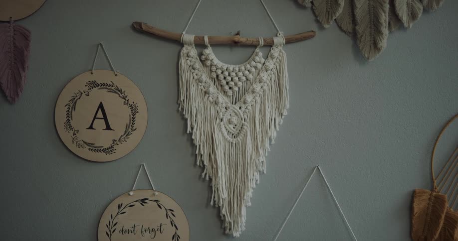 A macrame piece with white rope hangs on a blue wall