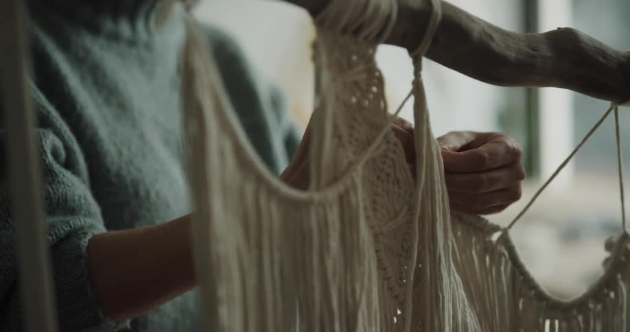 A woman is making something with yarn indoors
