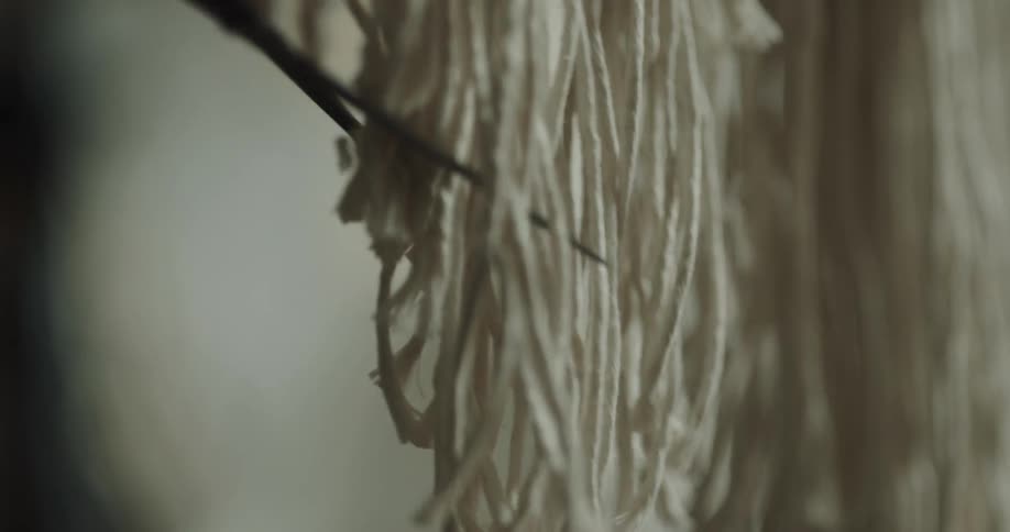 A person uses a pair of scissors to trim the edge on the fringes of a decoration