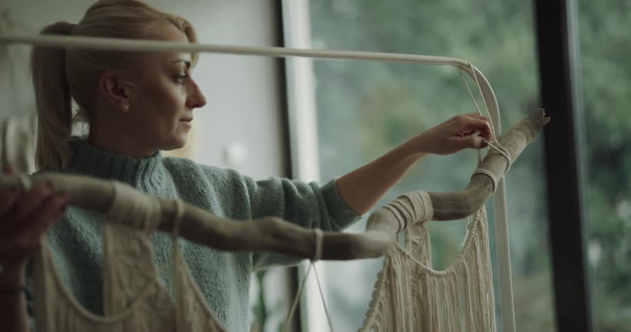A woman moves a log with a macrame piece in a room