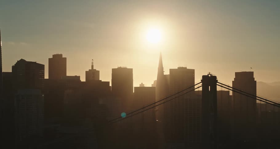 A bridge with a city skyline with buildings and skyscrapers with the sky and clouds in the background