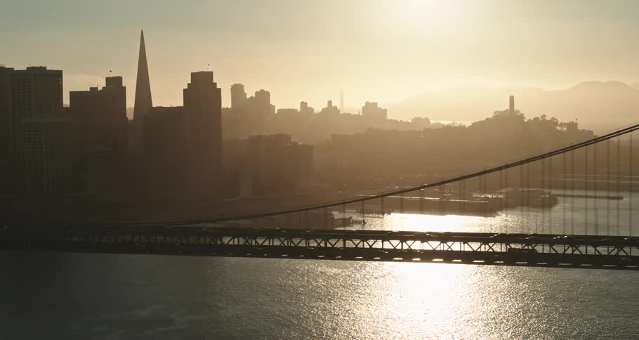 Cars are driving on a bridge near a downtown city at dusk