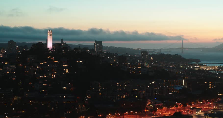 A brightly lit landmark stands above the darkened city skyline of san francisco